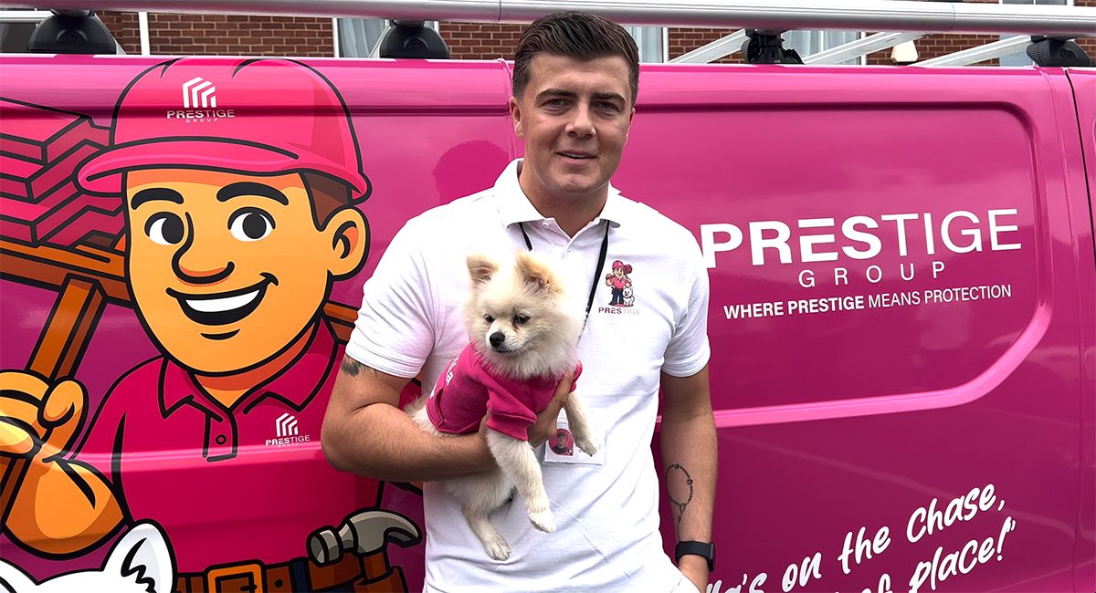 Luke from Prestige Roof holding Bella in front of the bright pink company van