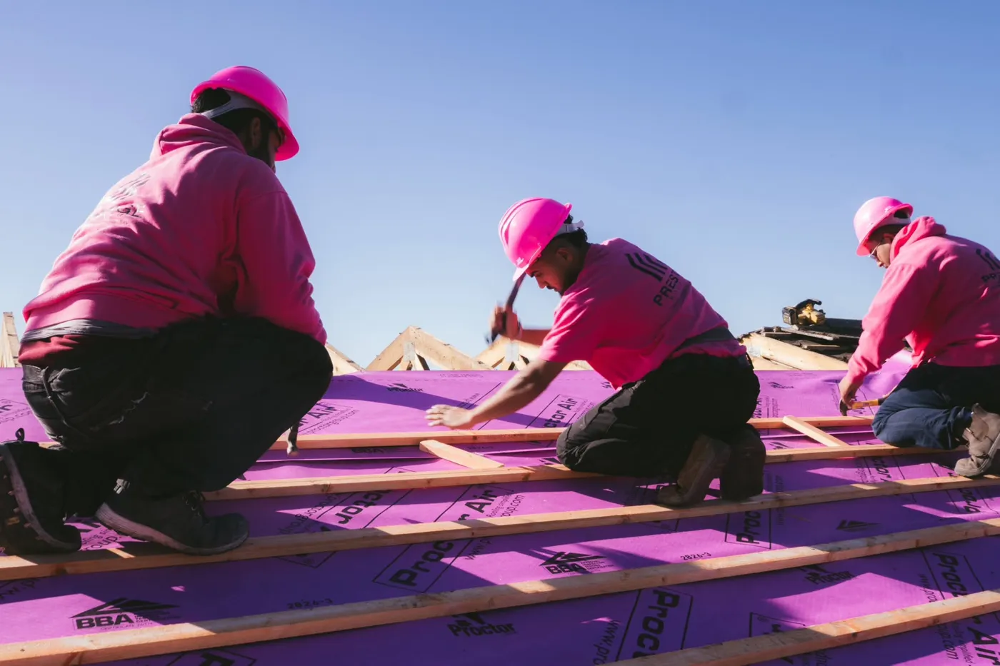 The Prestige Roof team in pink hard hats fixing new battens on a roof replacement
